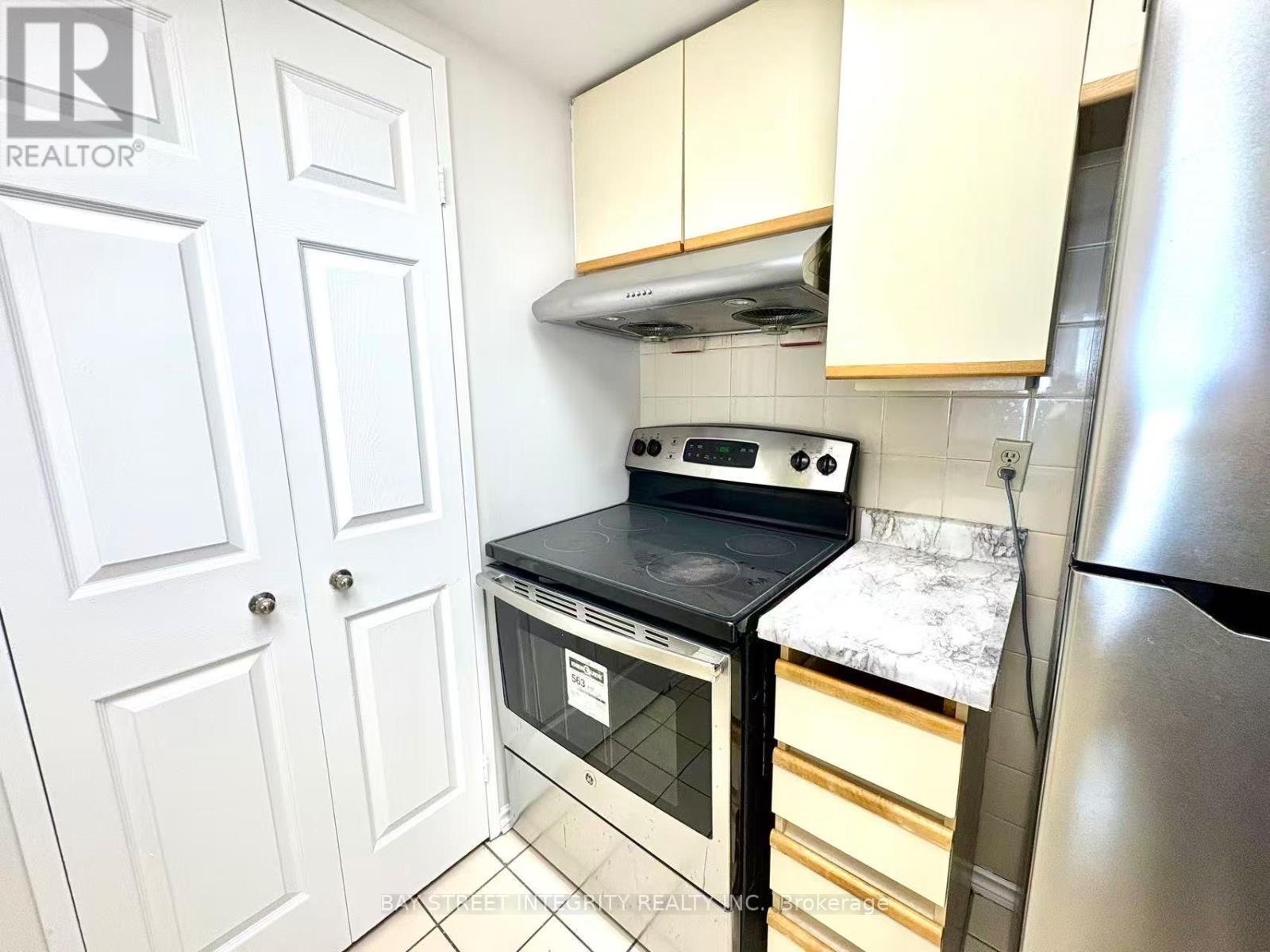 A kitchen with a stove top oven and a refrigerator.