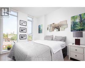 A bedroom with a large bed, a nightstand with a lamp, and pictures on the wall.