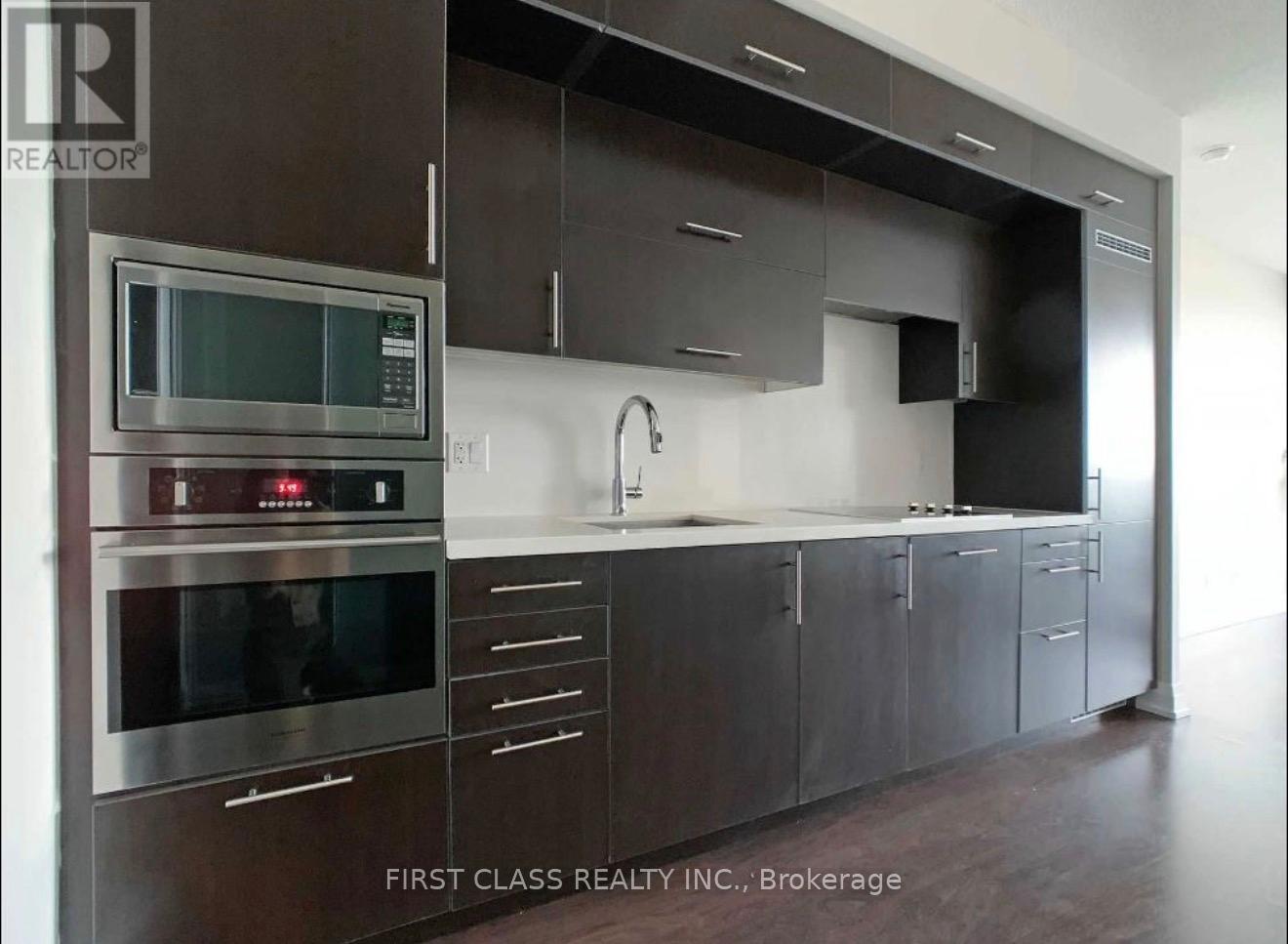 A modern kitchen with dark brown cabinets and stainless steel appliances.