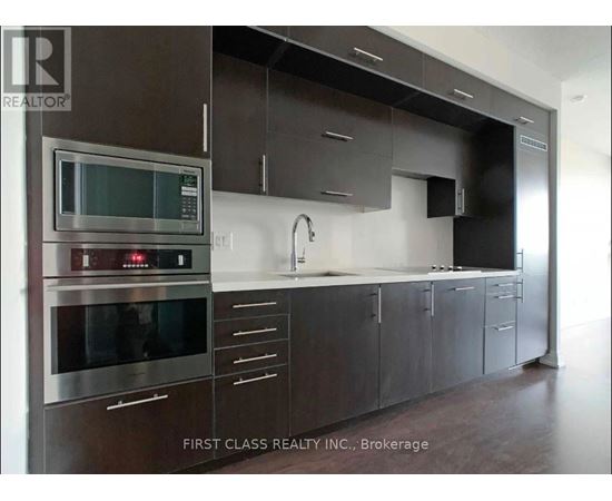 A modern kitchen with dark brown cabinets and stainless steel appliances.
