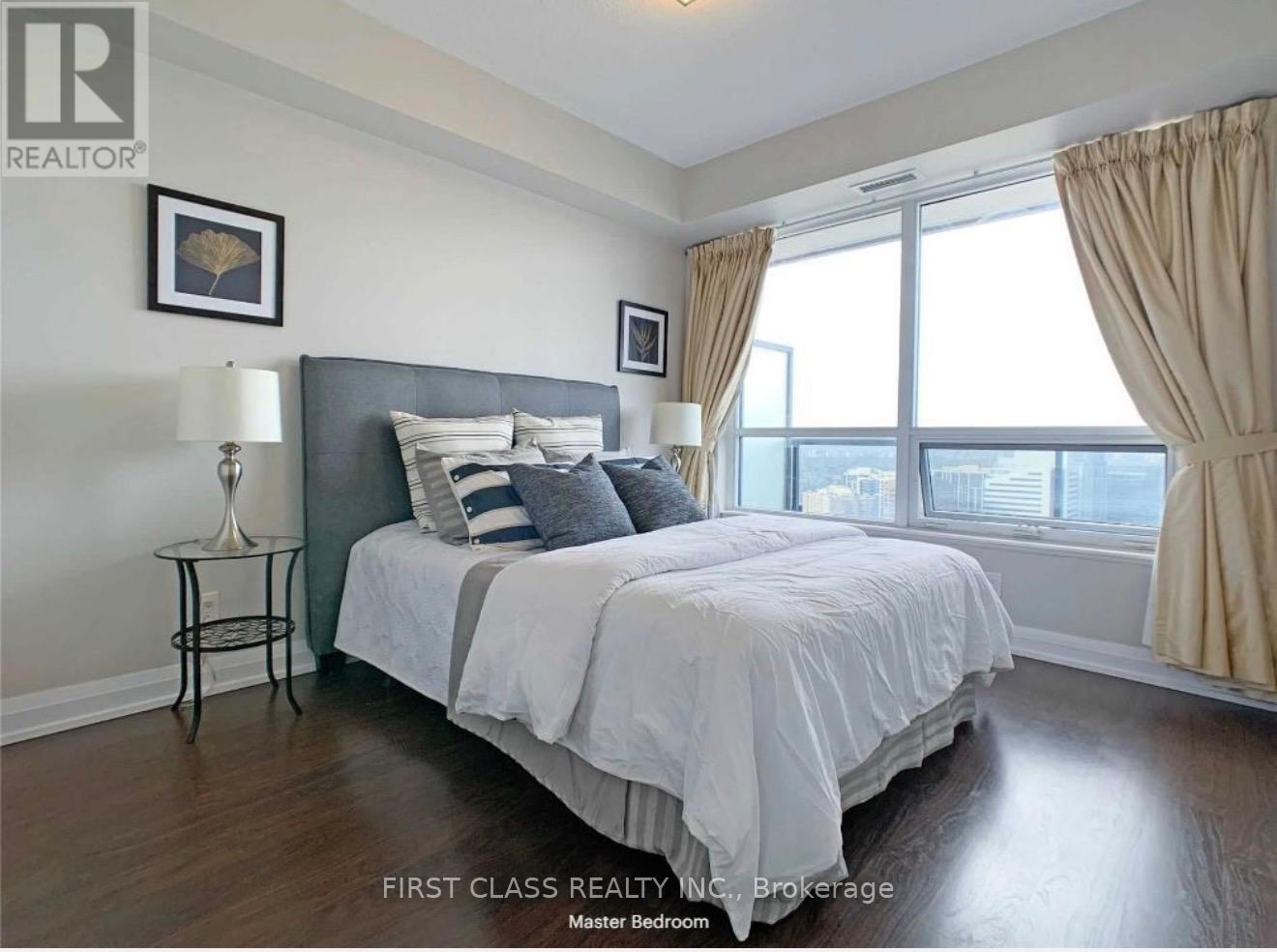A bedroom with a large bed and a window with curtains.