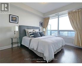 A bedroom with a large bed and a window with curtains.