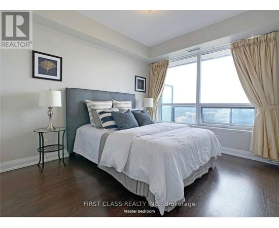 A bedroom with a large bed and a window with curtains.