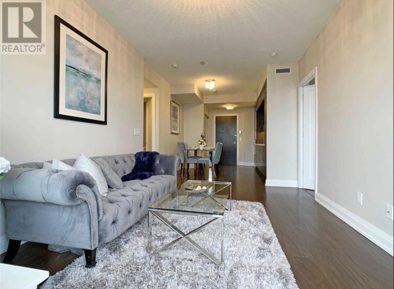 A living room with a grey couch and a glass coffee table.