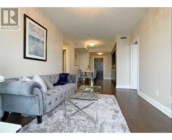 A living room with a grey couch and a glass coffee table.