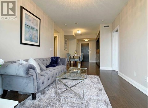 A living room with a grey couch and a glass coffee table.