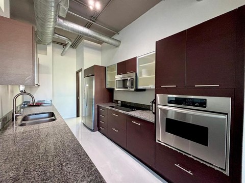 A kitchen with dark brown cabinets and stainless steel appliances.