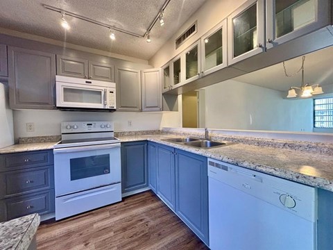 A kitchen with a white oven and microwave, a white sink, and a white dishwasher.