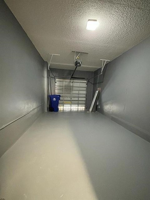 A long, narrow hallway with a blue bin and a metal staircase.