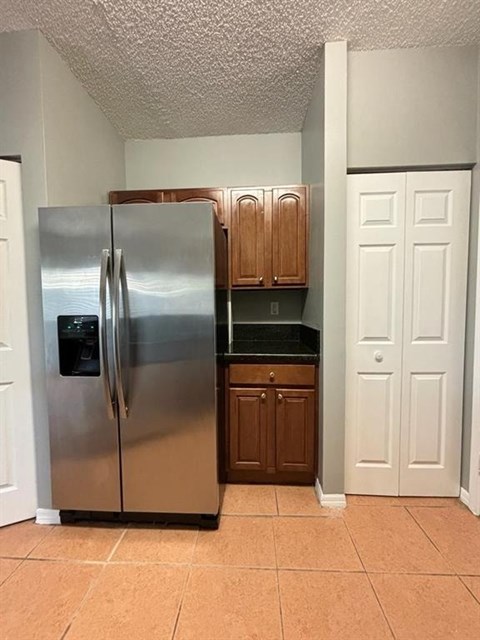A stainless steel refrigerator in a kitchen with brown cabinets.