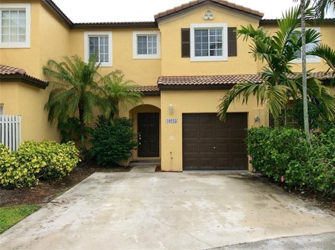 A yellow house with a brown garage door.