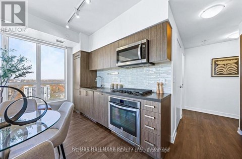 A modern kitchen with a glass table and stainless steel appliances.