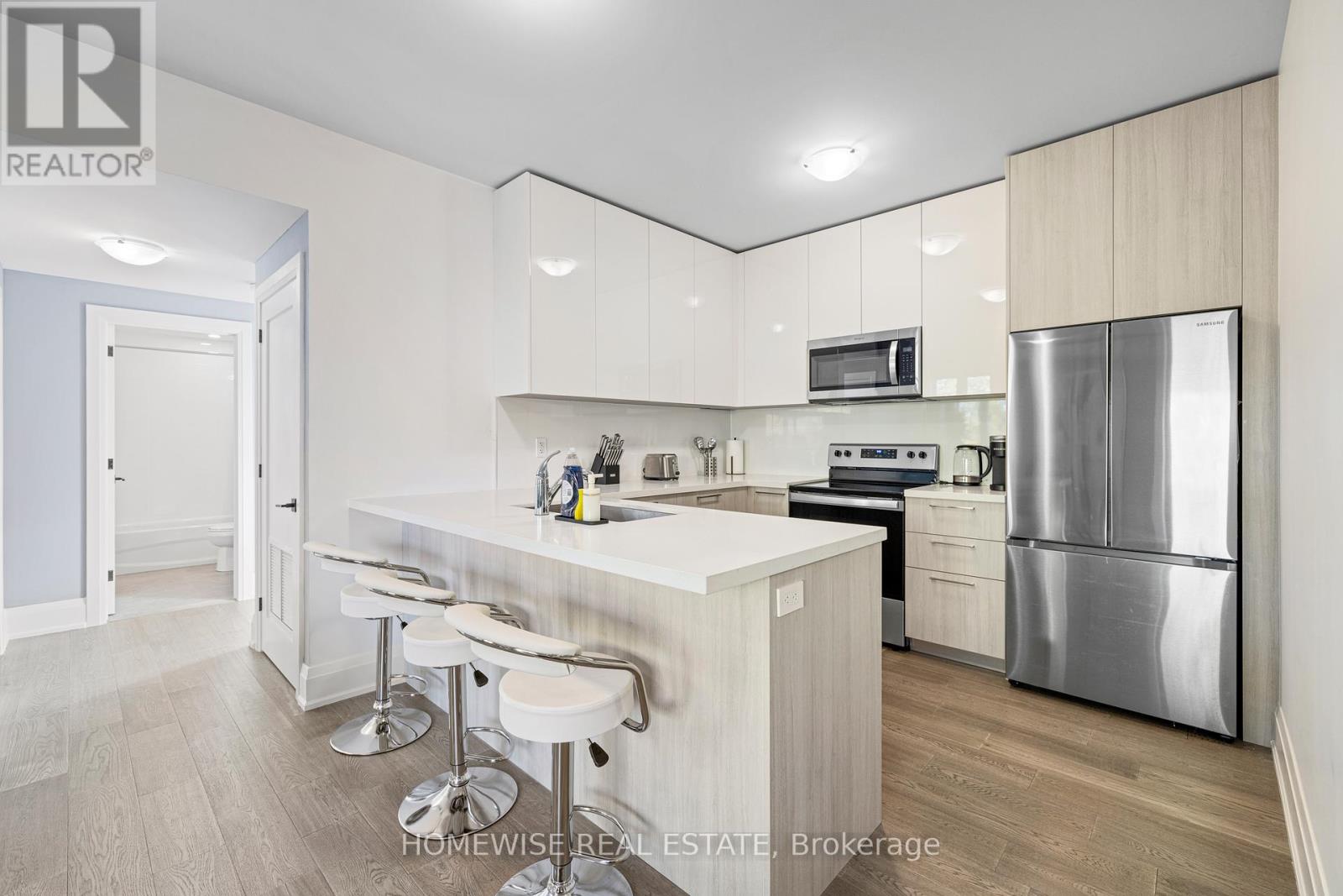 A kitchen with a bar stool and a refrigerator.