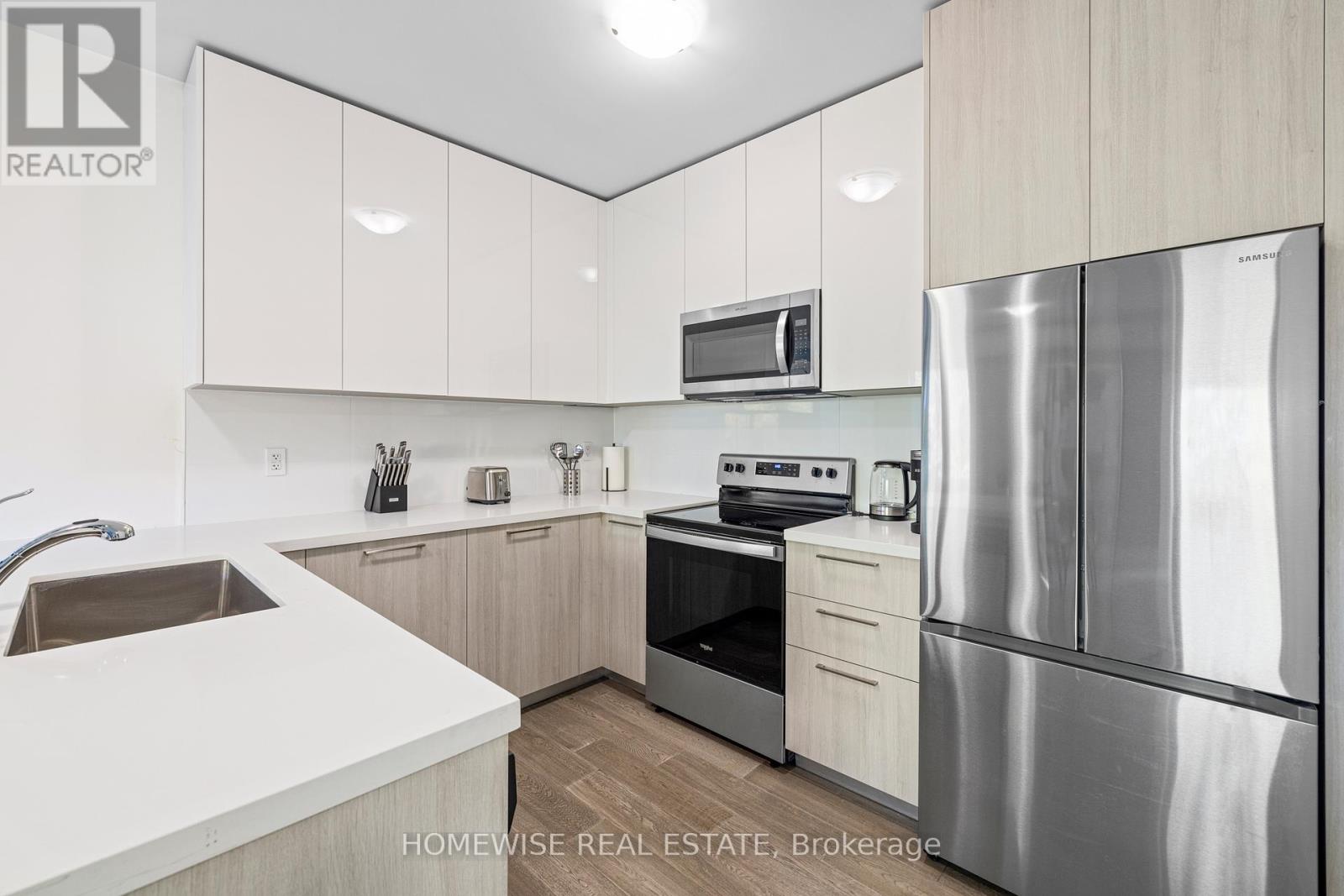 A modern kitchen with white cabinets and stainless steel appliances.