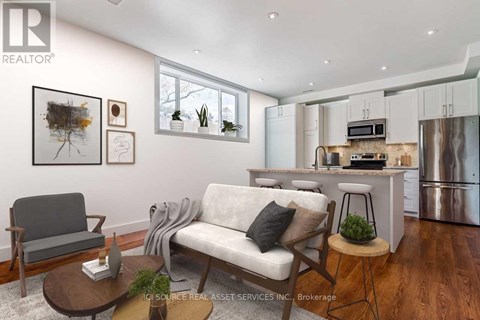 A modern living room with a grey sofa, a wooden coffee table, and a kitchen area in the background.
