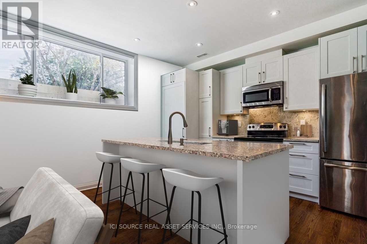A modern kitchen with a granite countertop and stainless steel appliances.