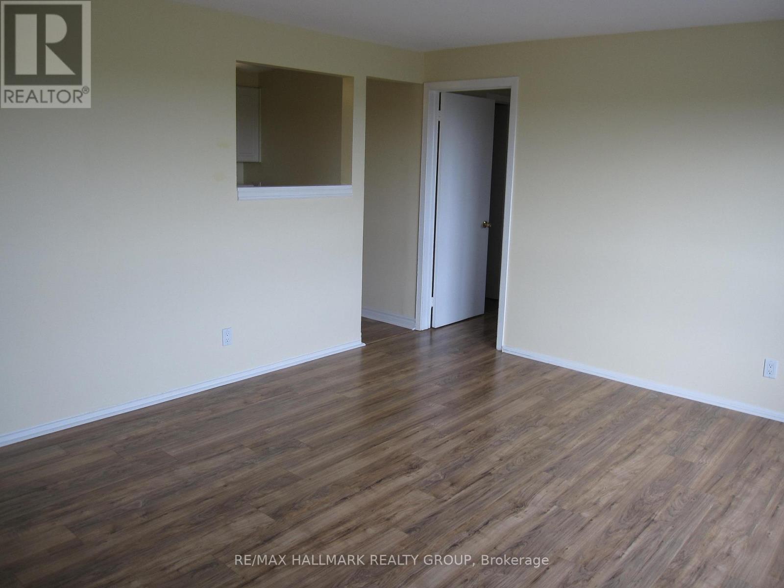 A room with wooden flooring and a door on the right side.