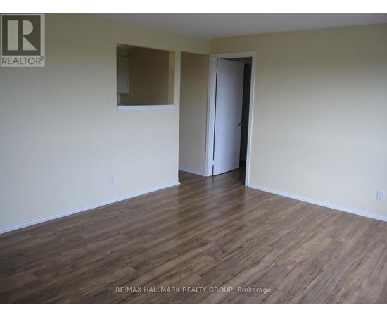 A room with wooden flooring and a door on the right side.