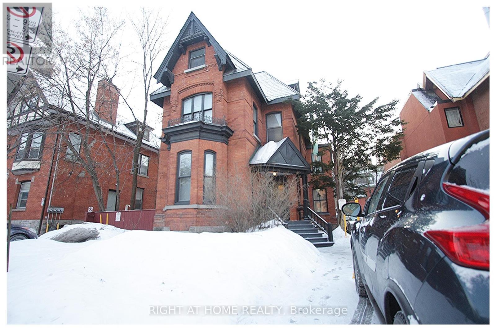 A red brick house with a black car parked in front.