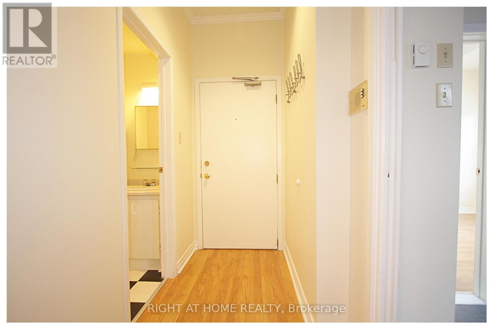 A hallway with a white door and a light switch on the wall.