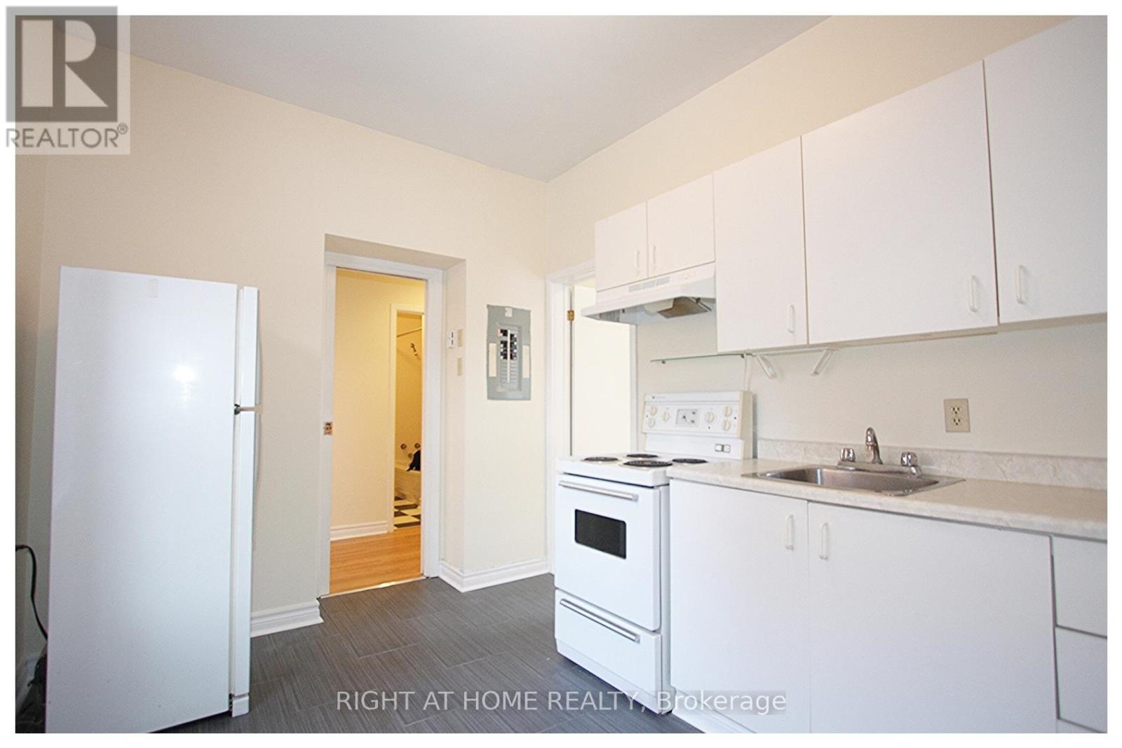 A white kitchen with a refrigerator, oven, and sink.