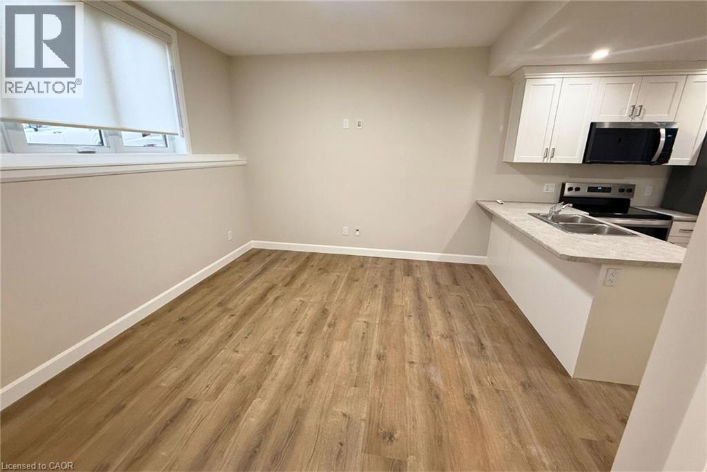 A room with wooden flooring and a kitchenette area.