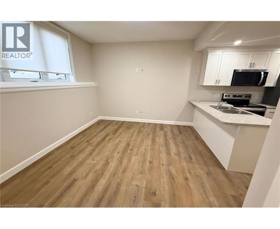 A room with wooden flooring and a kitchenette area.