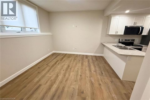 A room with wooden flooring and a kitchenette area.