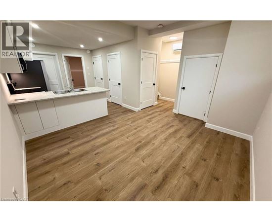 A spacious room with wooden flooring and white walls.