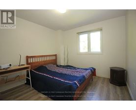 A bedroom with a bed, nightstand, and window.