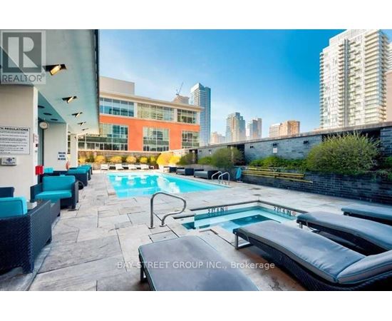 A pool area with loungers and a view of the city skyline.