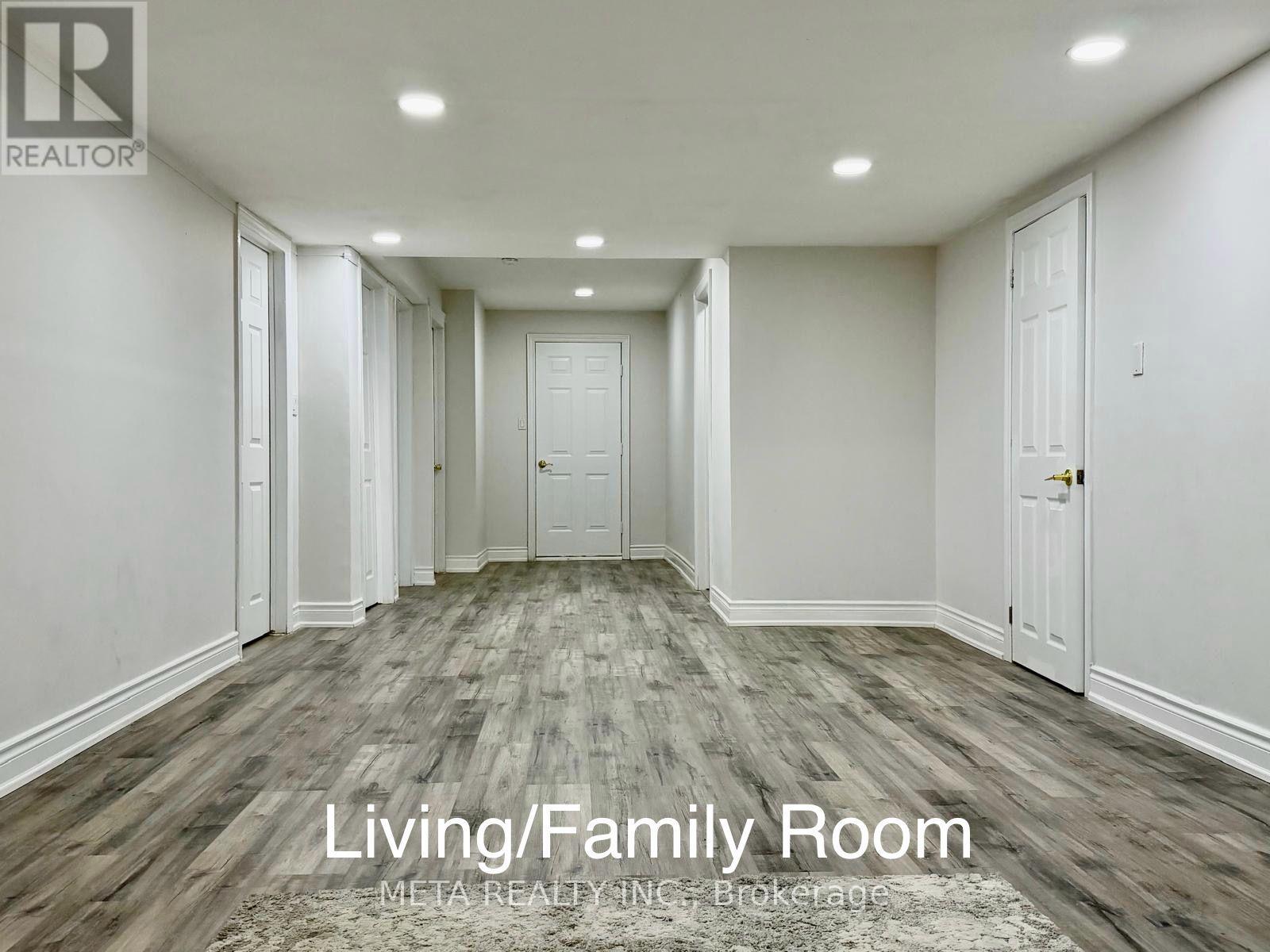 A spacious living/family room with wood flooring and white walls.