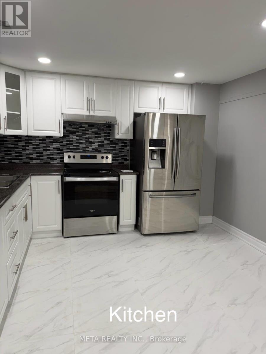 A kitchen with white cabinets and a refrigerator.