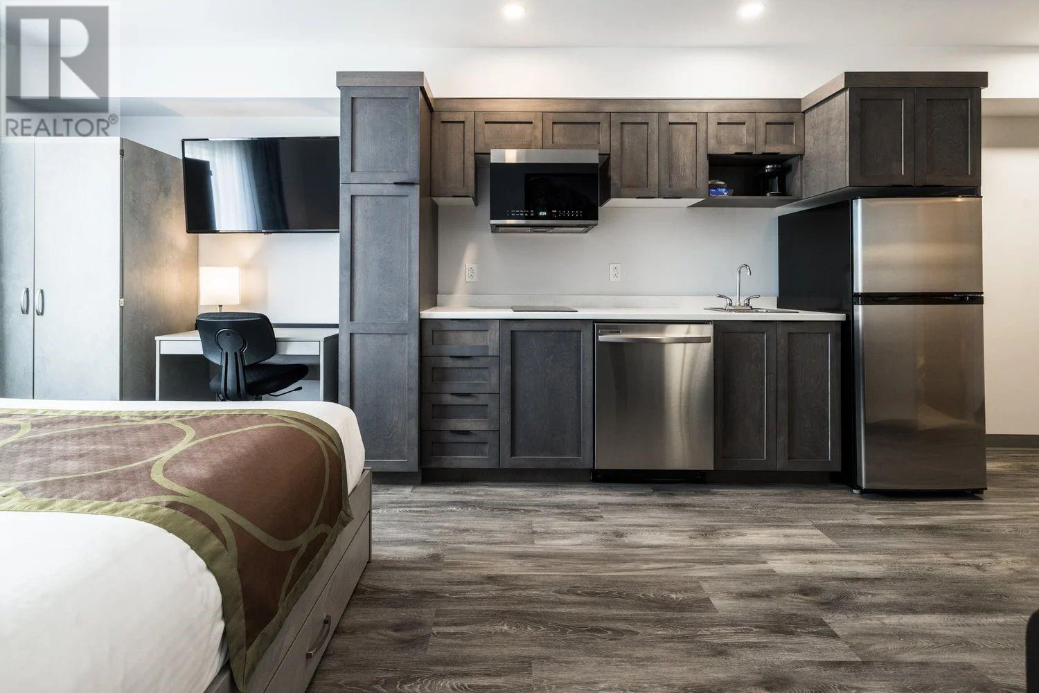 A modern kitchen with dark wood cabinets and stainless steel appliances.
