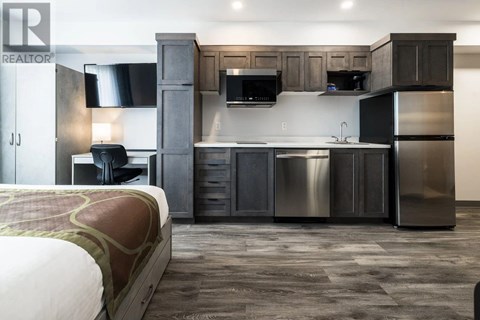 A modern kitchen with dark wood cabinets and stainless steel appliances.