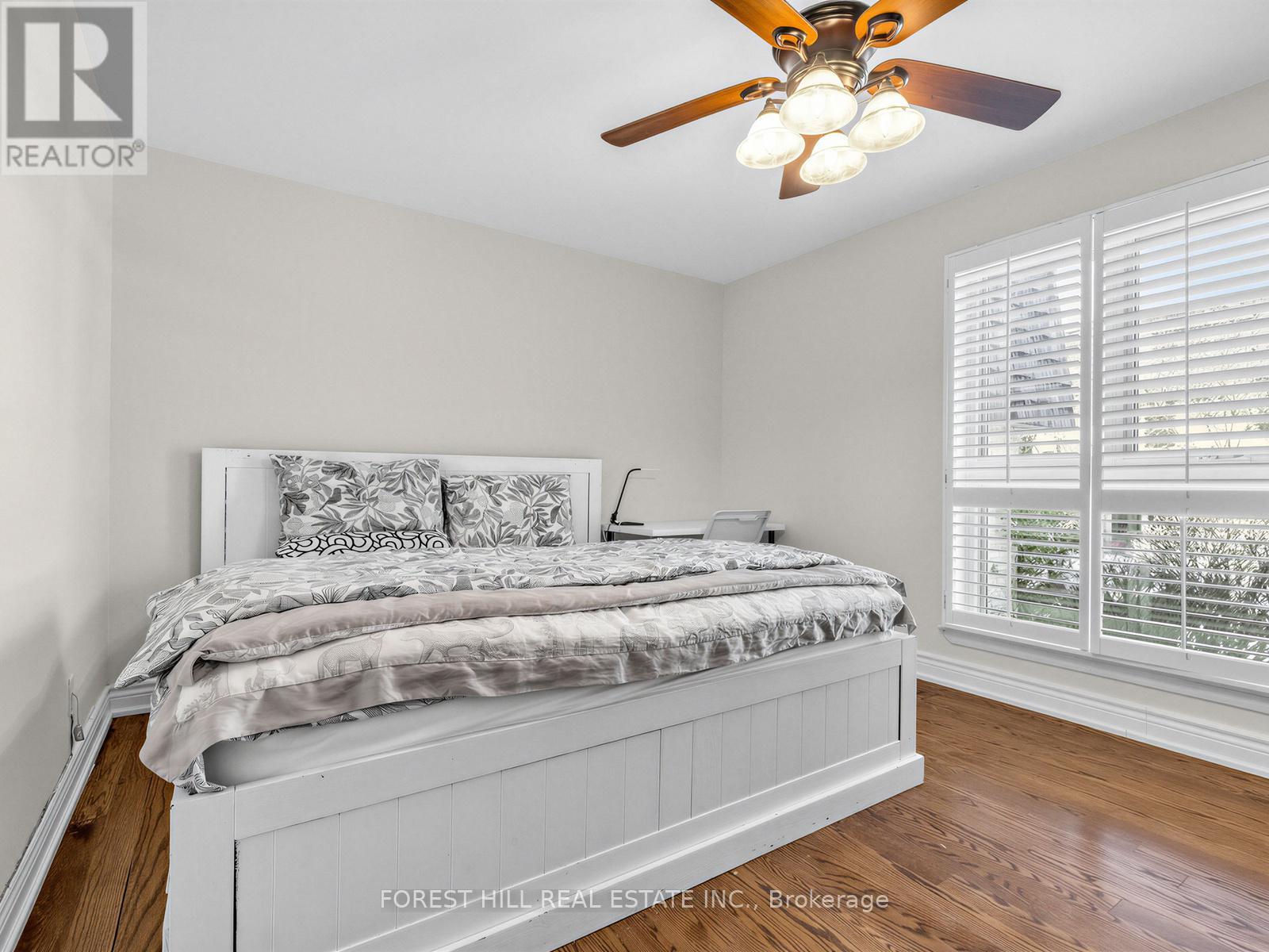 A bedroom with a large bed and a ceiling fan.