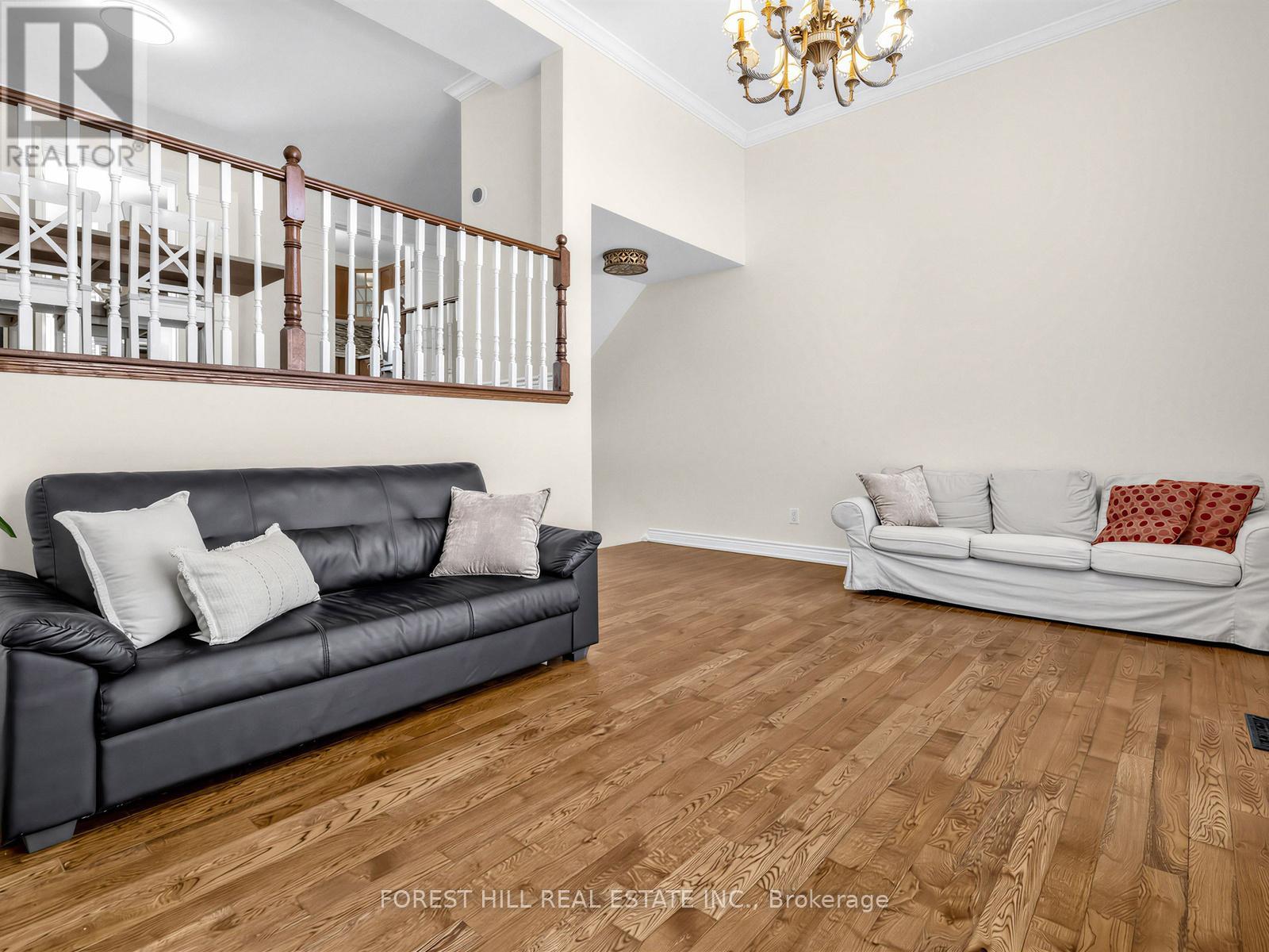 A living room with a black couch and a white couch in the background.