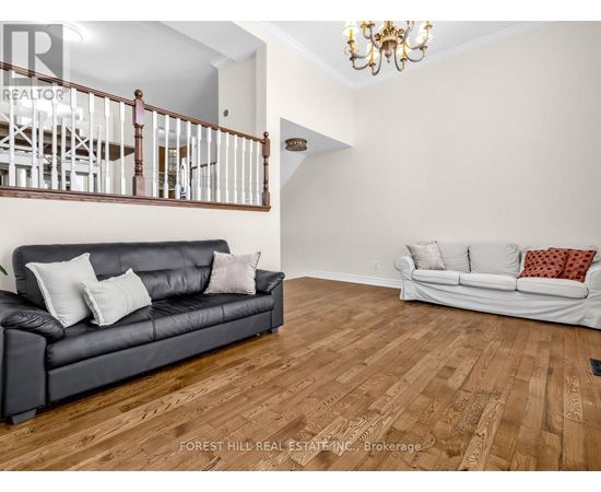 A living room with a black couch and a white couch in the background.