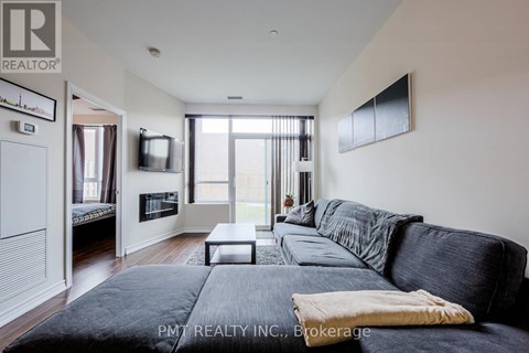 A living room with a black couch and a flat screen TV mounted on the wall.