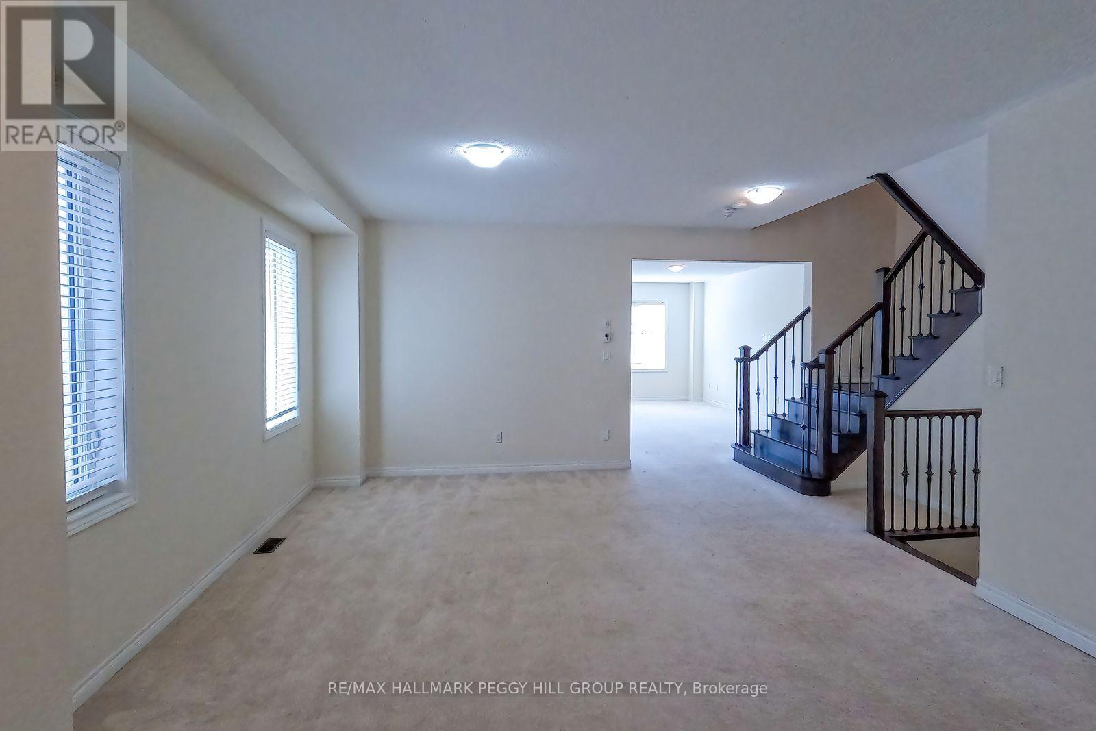 A spacious room with a staircase and a window.