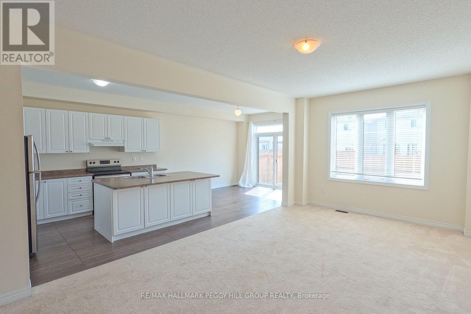 A spacious kitchen and living room with white cabinets and a large island.