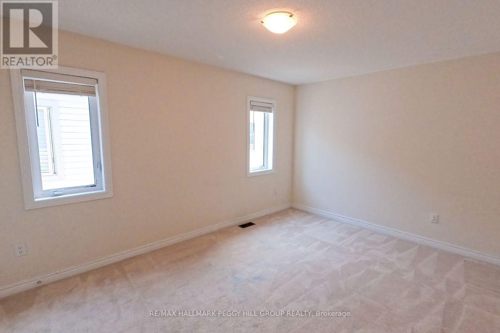 A white bedroom with a window and carpeted floor.