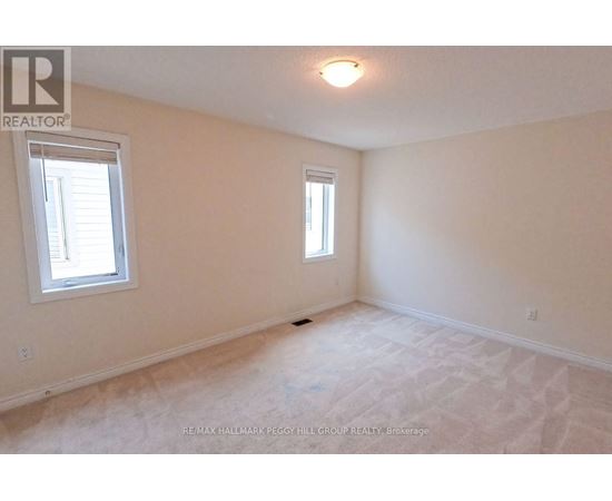 A white bedroom with a window and carpeted floor.