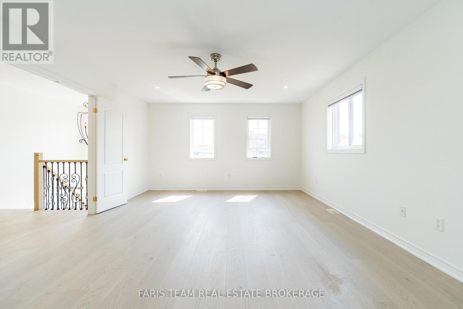 A spacious room with a ceiling fan and hardwood floors.