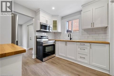 A modern kitchen with white cabinets and a wooden countertop.