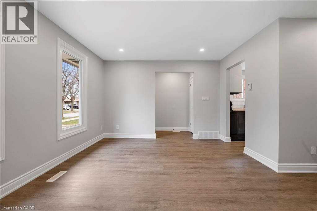 A spacious room with wooden flooring and white walls.