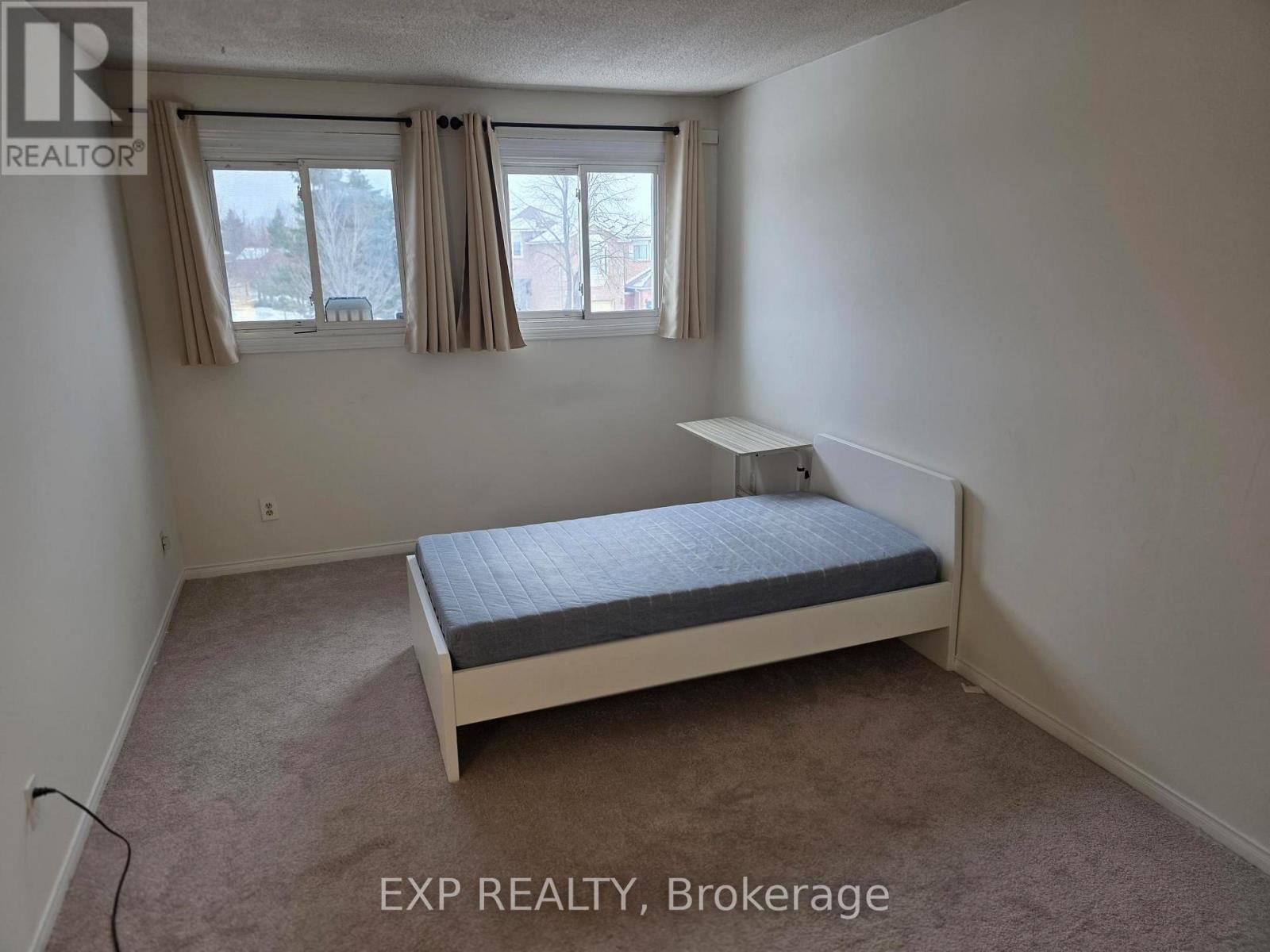 A bedroom with a bed, desk, and window.