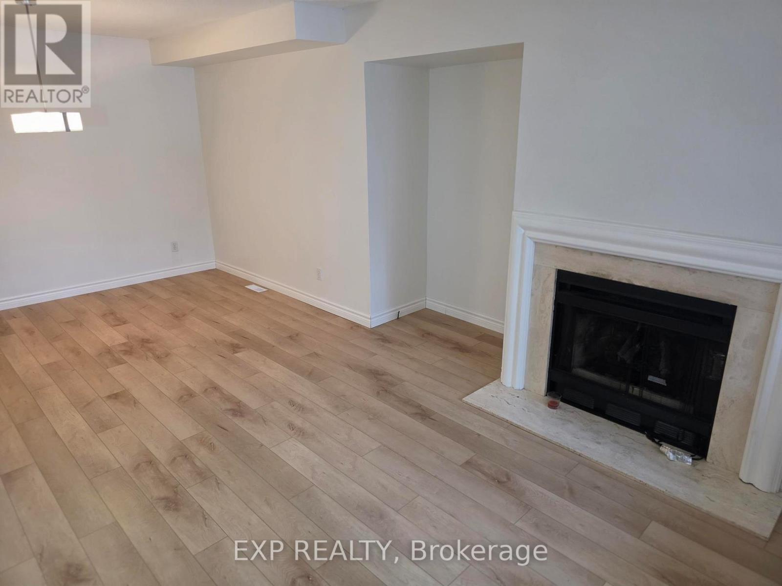 A room with a fireplace and wooden flooring.