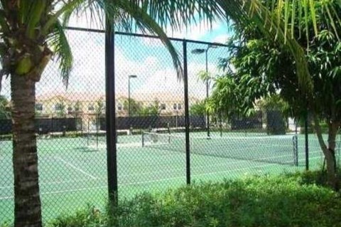 A tennis court surrounded by a fence and trees.