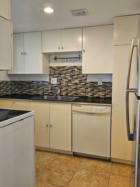 A kitchen with white cabinets and a black counter top.